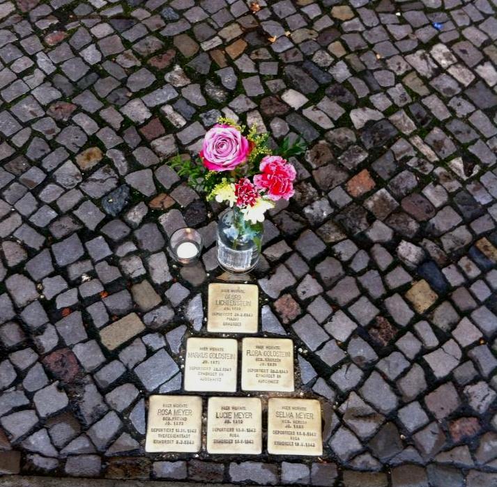 A candle and flowers placed at the Stolpersteine on the anniversary of Kristallnacht